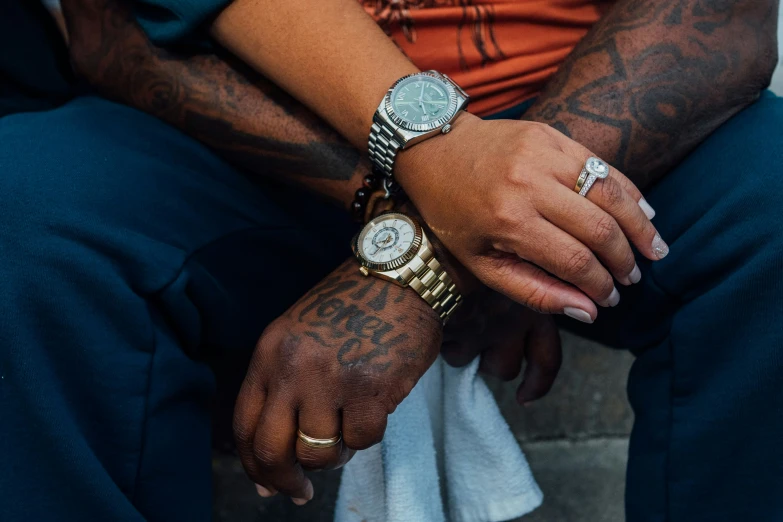 two tattooed people hold hands on their wrists