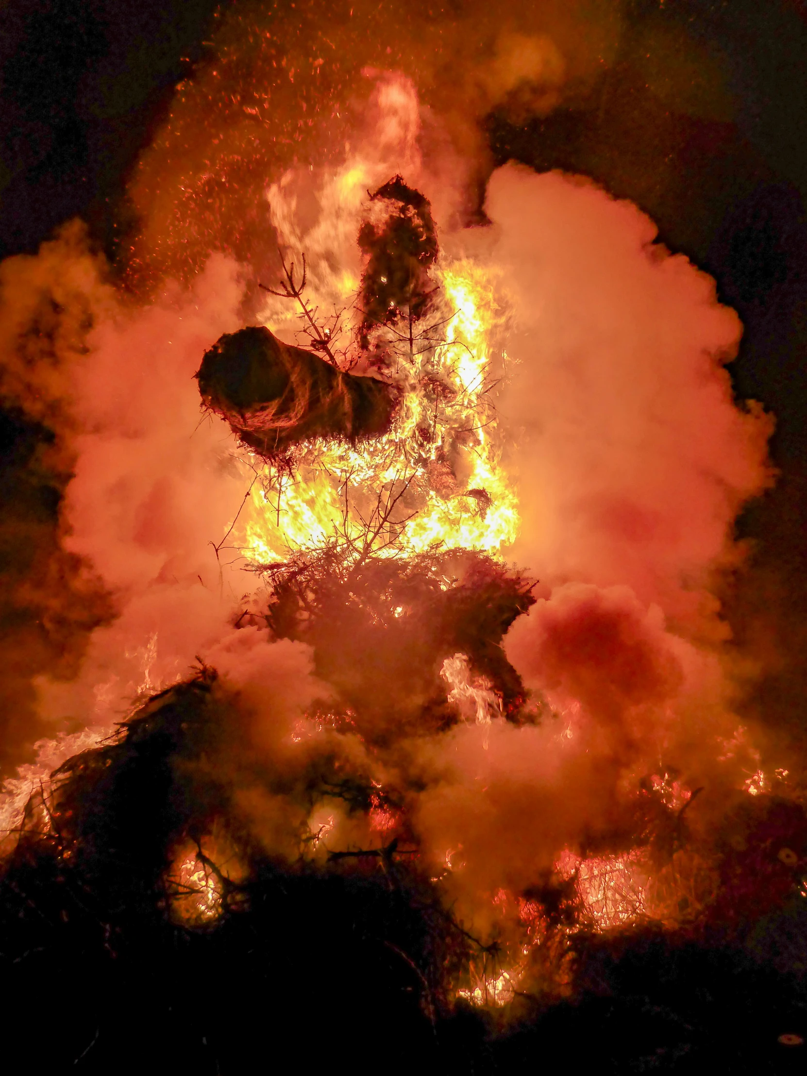 an aerial s shows flames as people stand under it