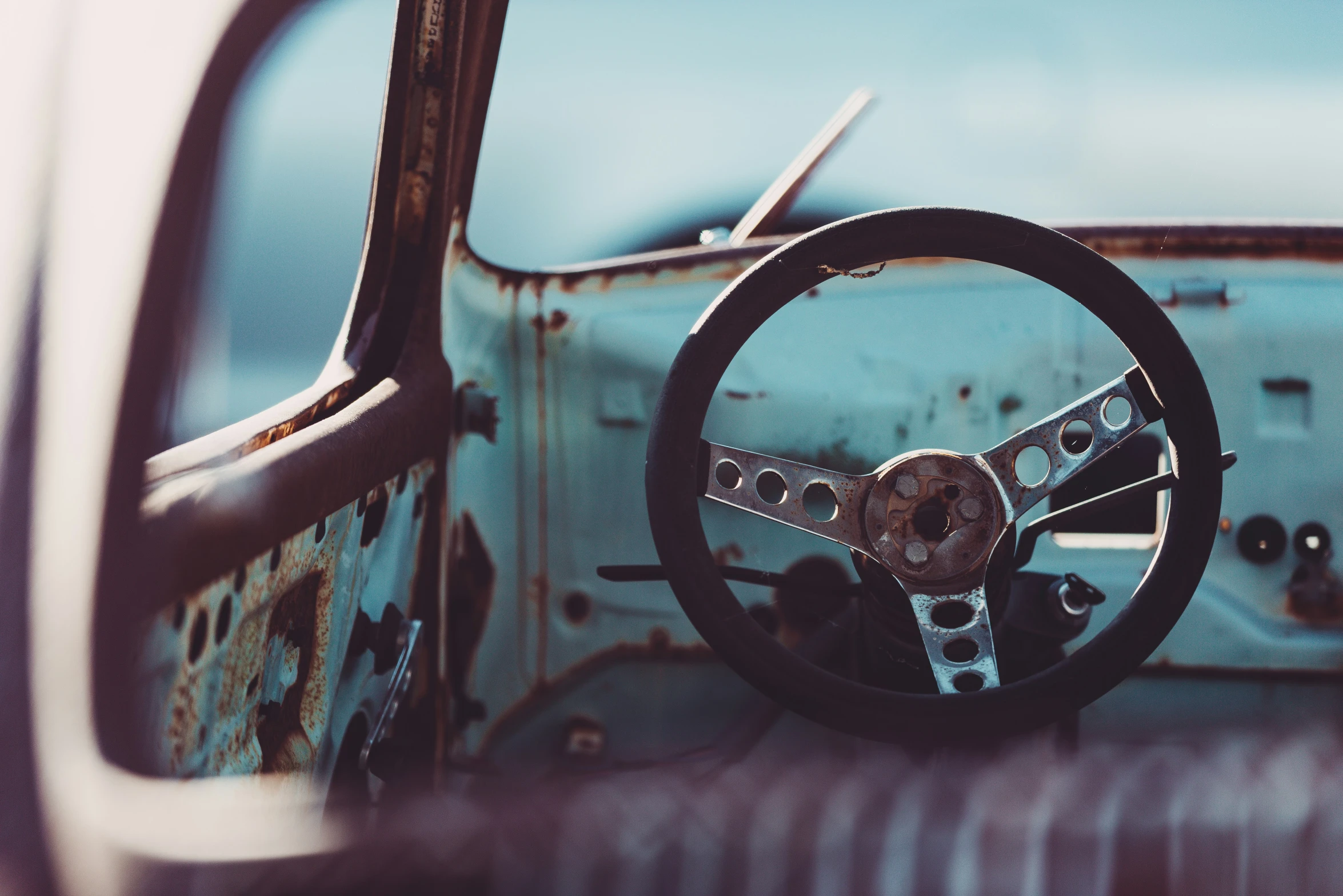 a rusty looking old car with the steering wheel up