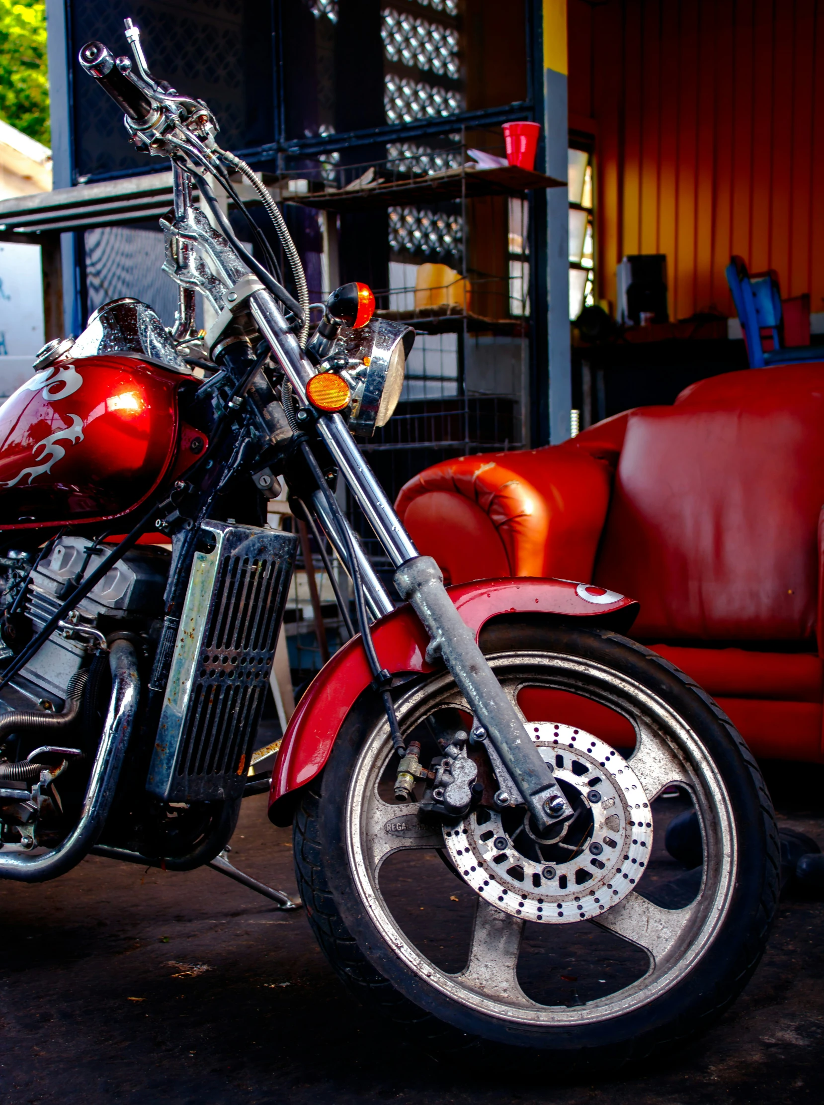 a red motorcycle parked on the street near a couch