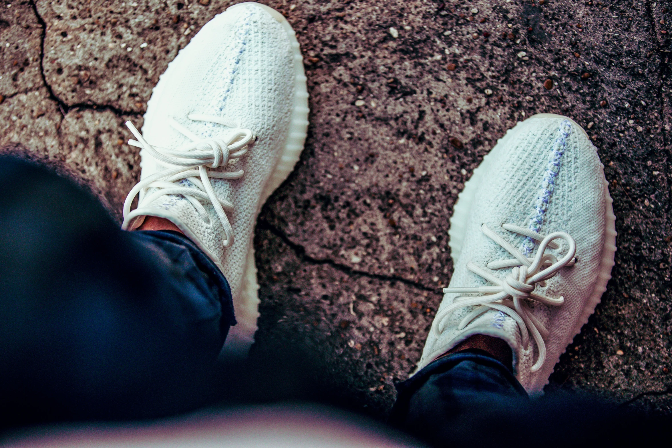 feet with white shoes standing on stone pavement