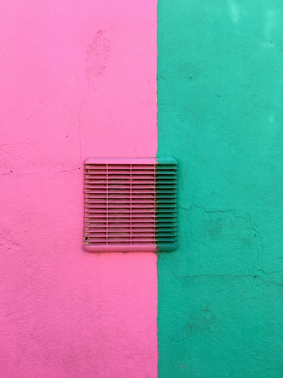 the window is above a square grate that is below pink and green