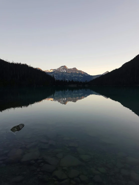 a mountain range is reflected in the still calm water