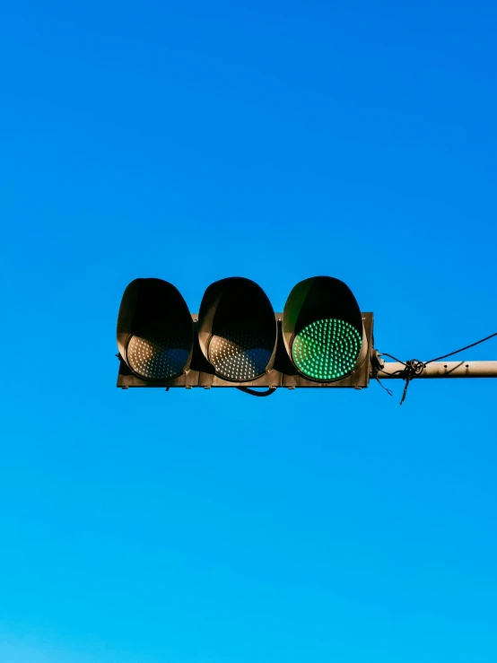 a green traffic signal with a sky background