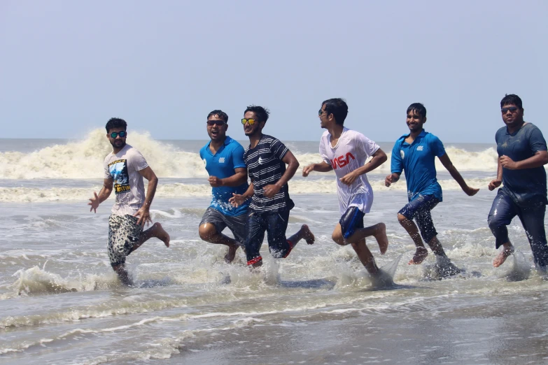 six men are running in the surf with blue and white shirts