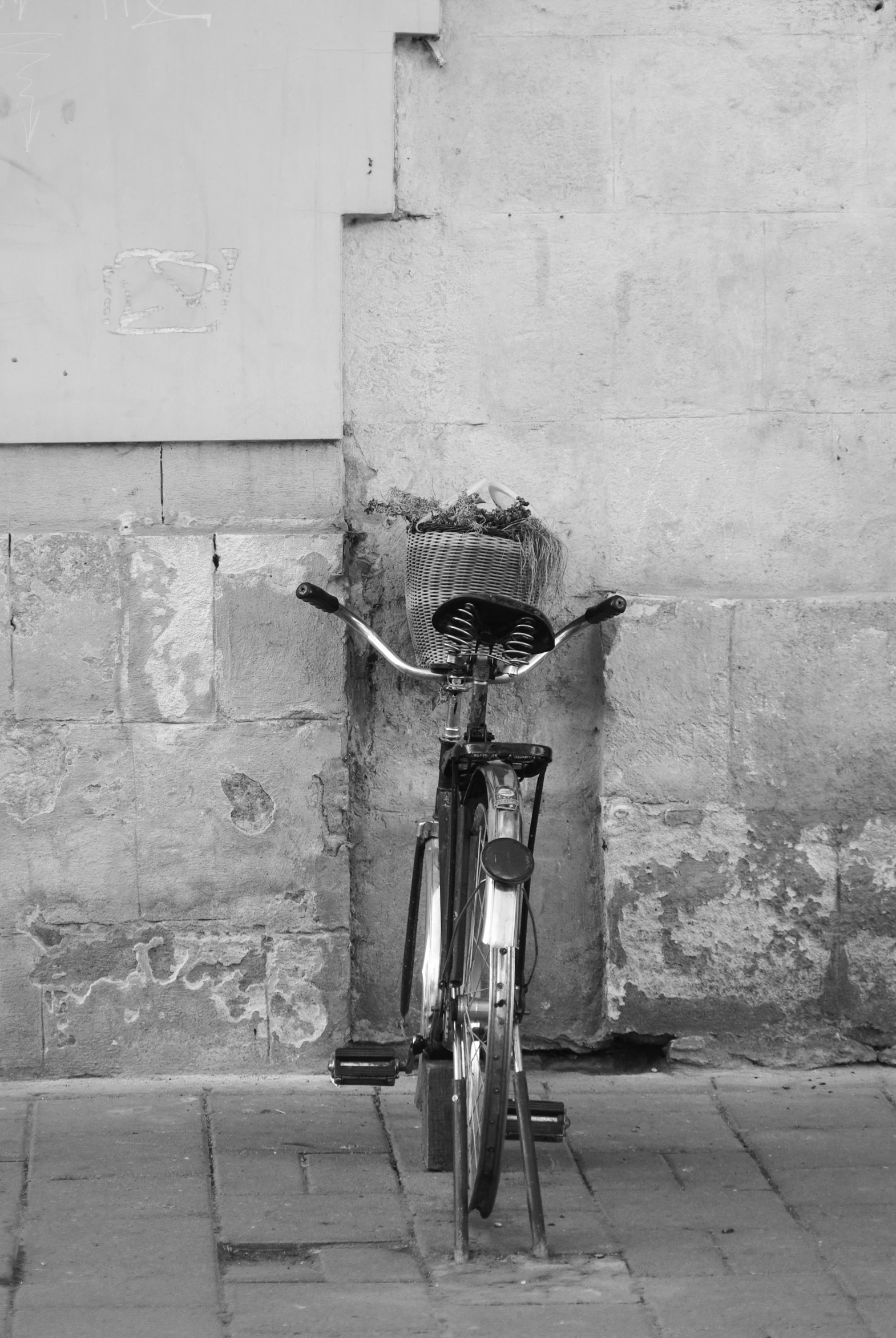 a bicycle parked in front of a wall on the side of a road