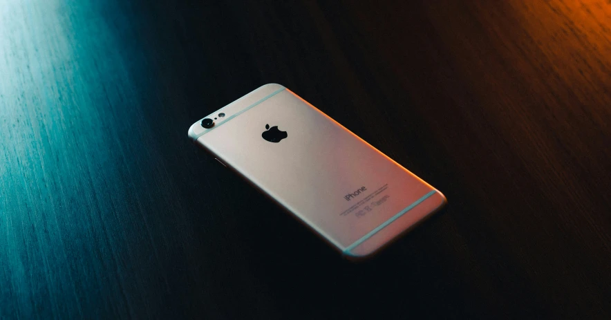 an apple phone sitting on top of a wooden table