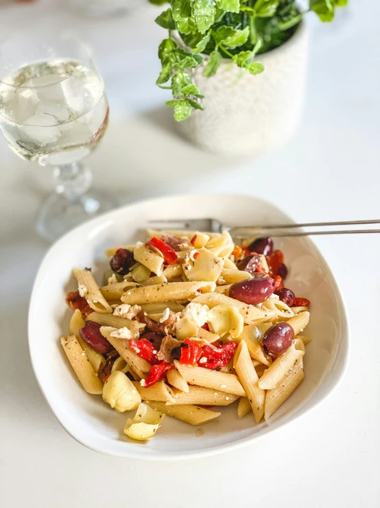 a bowl of pasta and salad sits on a table