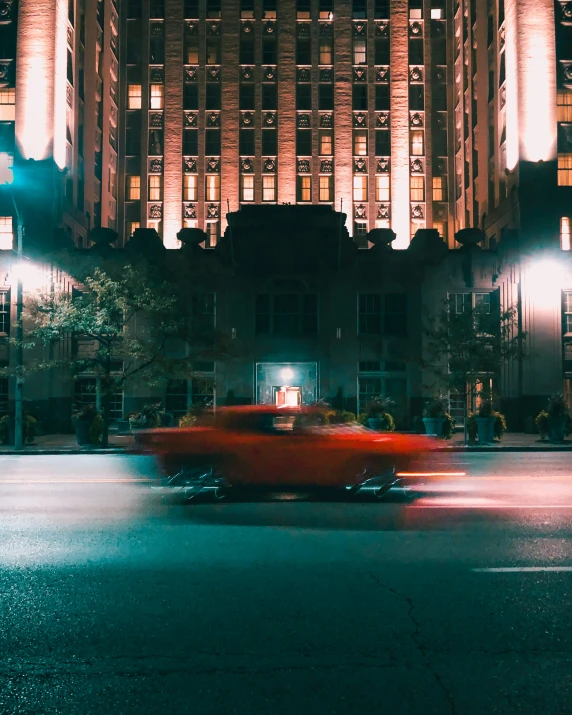 a red old car on a city street at night