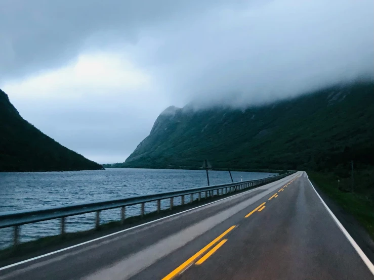 a highway near a mountain with a body of water