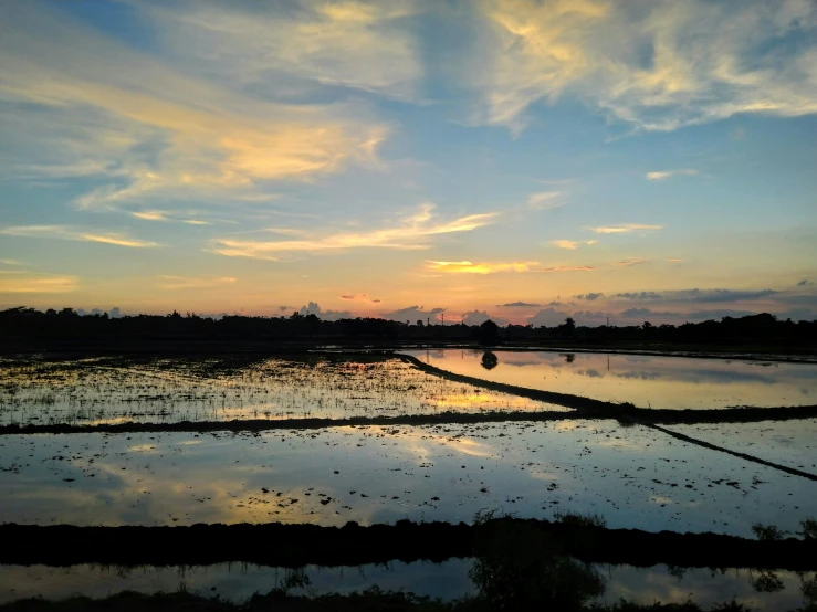 the sun sets over an empty river with water reflection