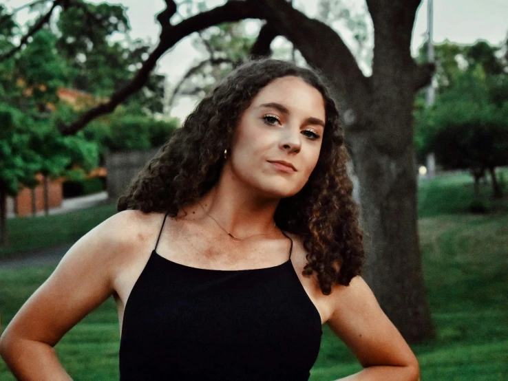 a woman standing in a park with her hands on her hips