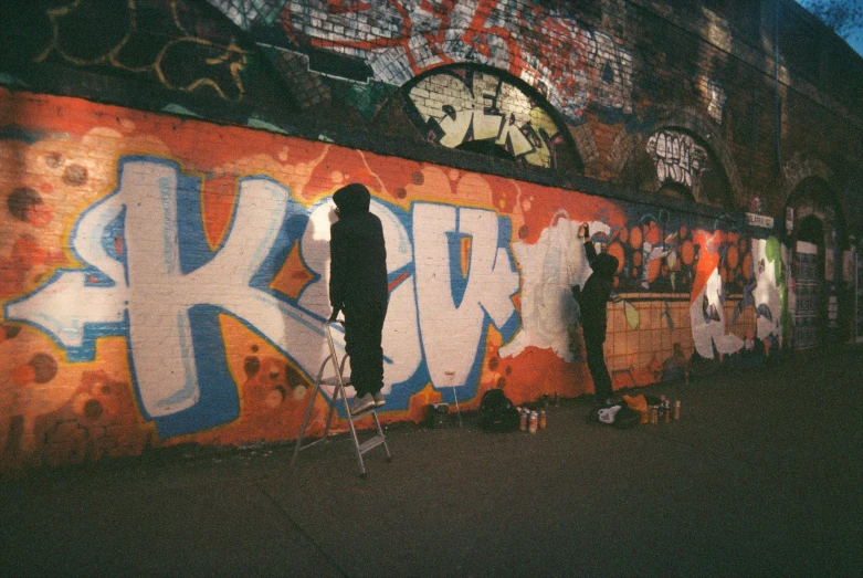 a group of men painting on a wall with graffiti