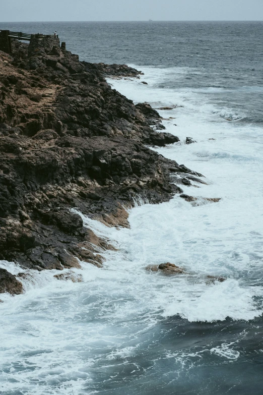 people walking up the side of a cliff near the ocean