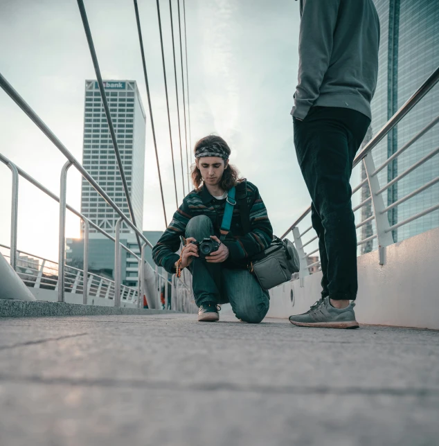 woman squatting next to a man on a street with building in the background