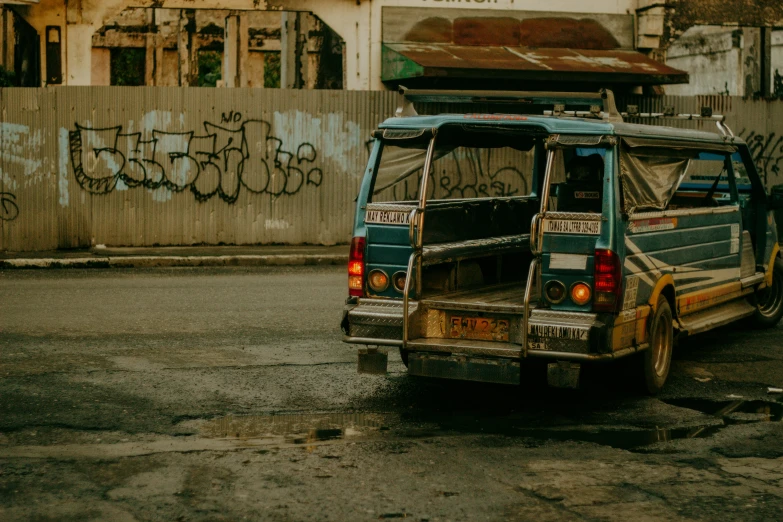 a blue van is in front of a rusty wall