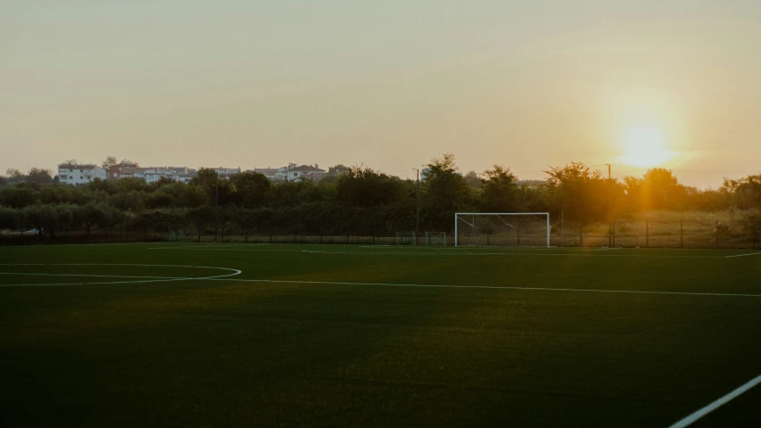 a soccer field with a sun set in the distance