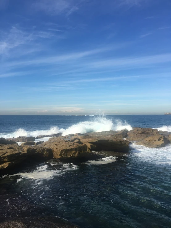 an ocean rocky shoreline with waves breaking against the rocks