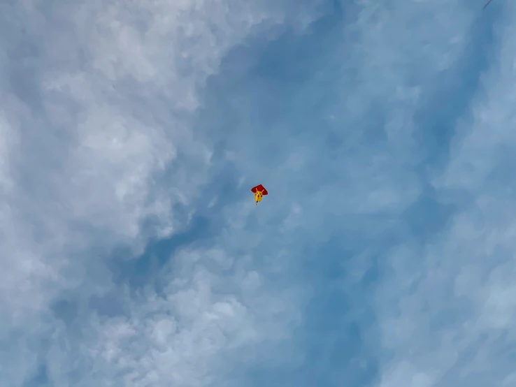 a person flying a red and yellow kite high in the sky