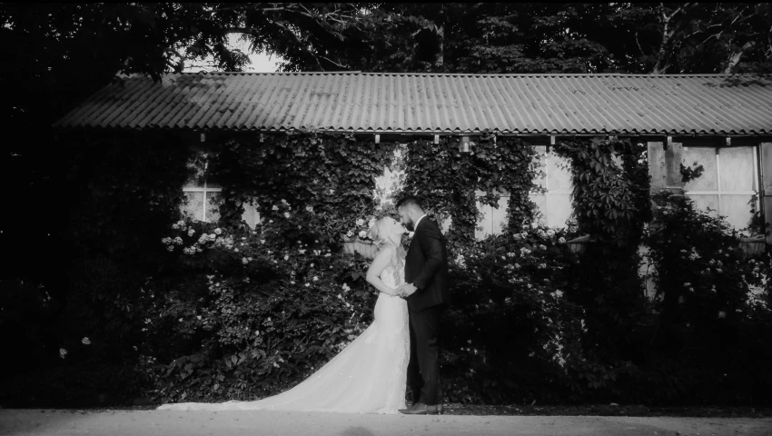 a bride and groom kiss near the ivy covered side of a house