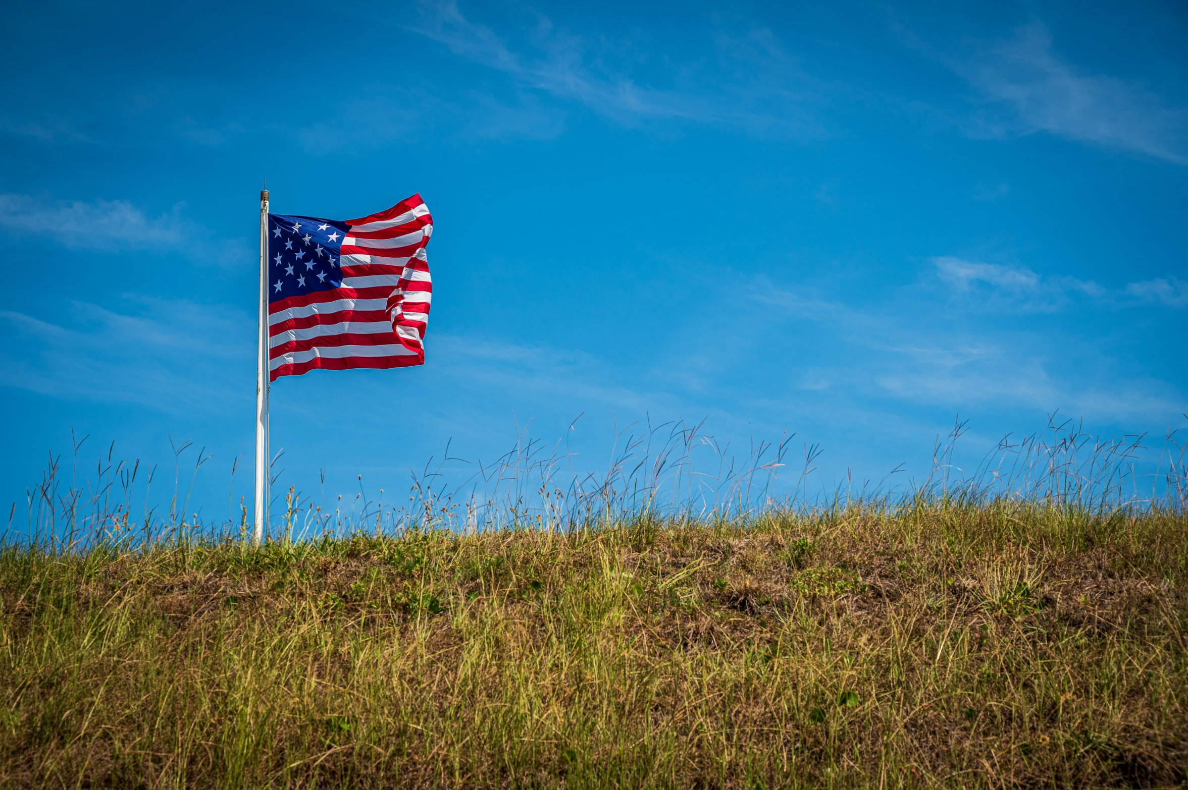 a flag flying on top of a grassy hill