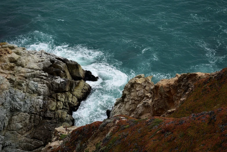a rock outcropping on the shore with crashing waves