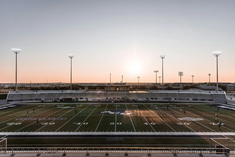 a football field with lights and bleachers in the background