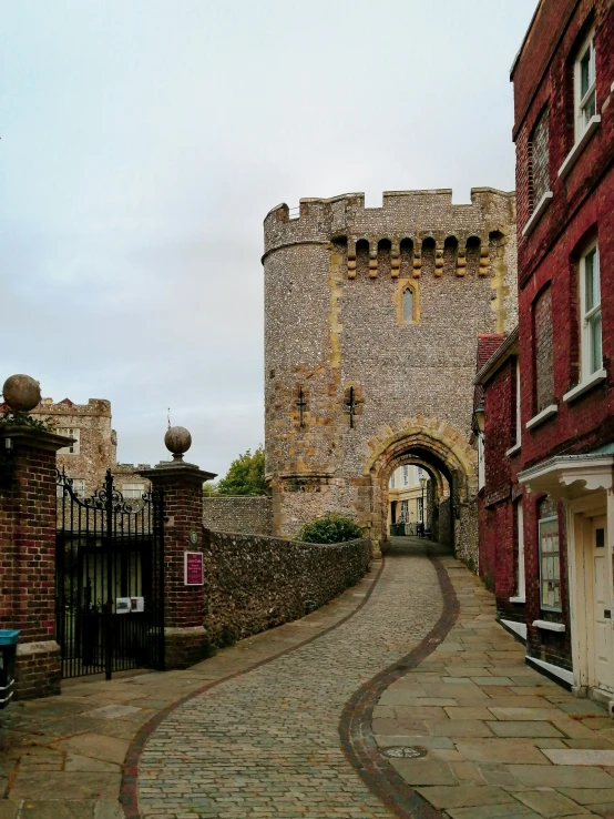 an archway leading to a small tower over a brick sidewalk