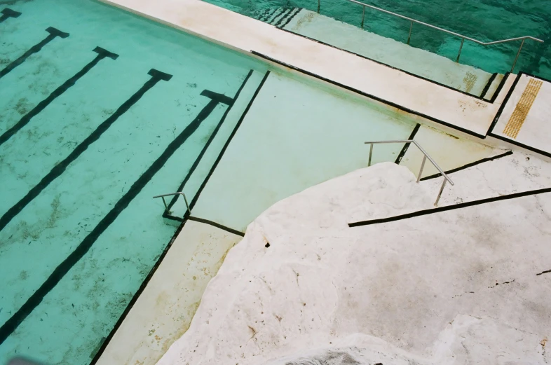 a man sits by a pool and looks out at the water