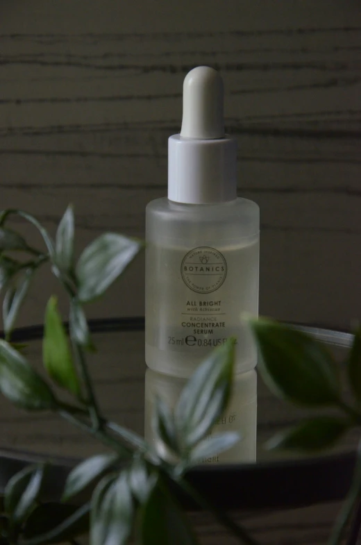 a bottle of white facial cleanser next to a green plant