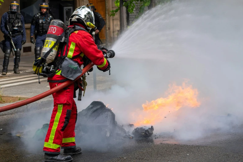 a firefighter using a hose to extinguish fire from a huge pile of rubble