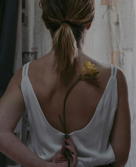 the woman is holding flowers in her hand and a long rope on her back