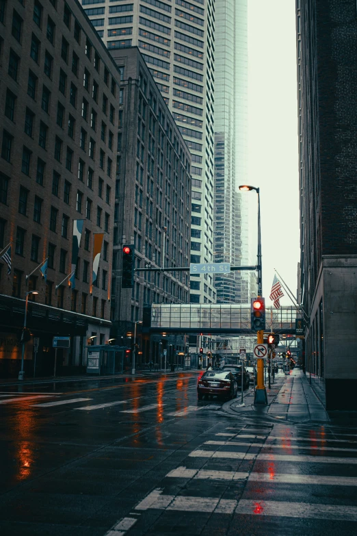 a city street with rain in the street and some tall buildings