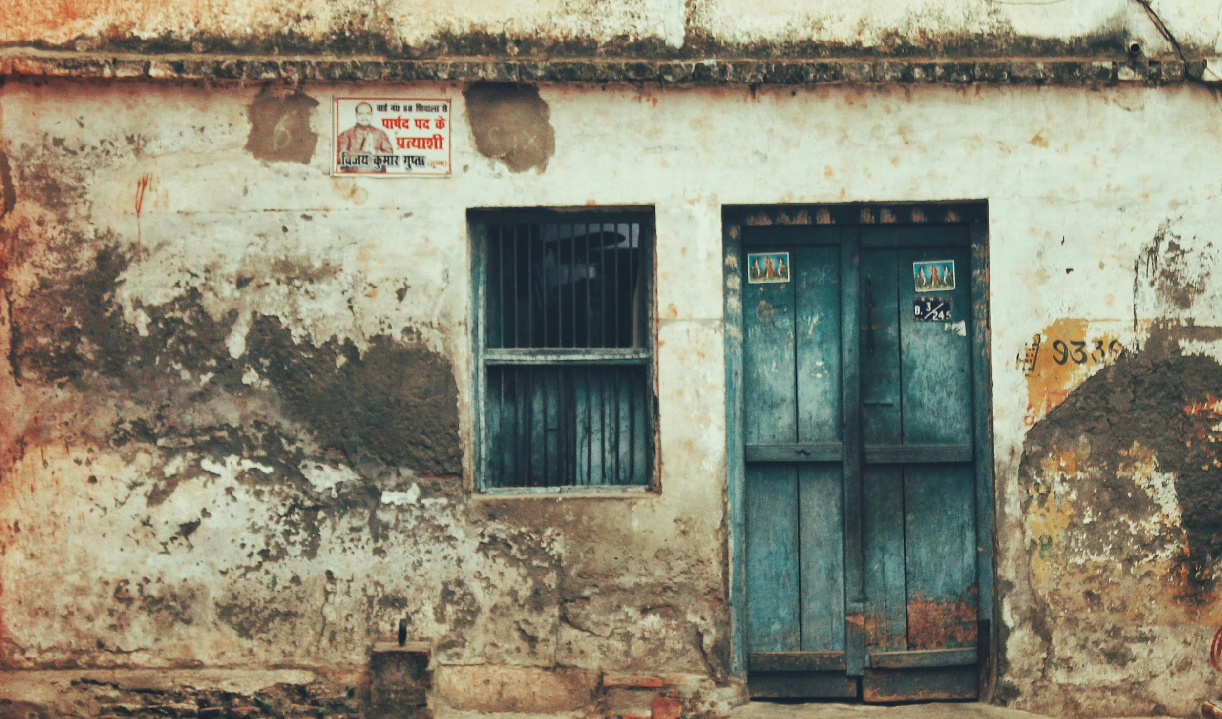 a dilapidated building with two windows and door