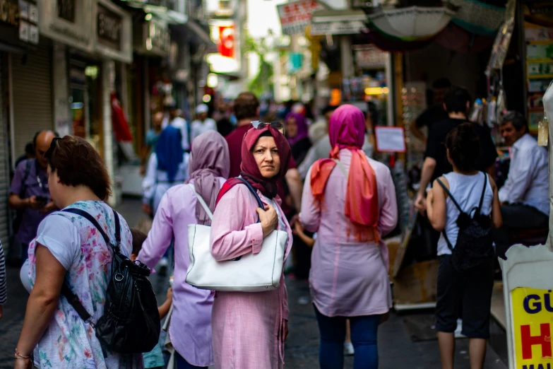 a woman with pink hair and a white purse walking on a busy street