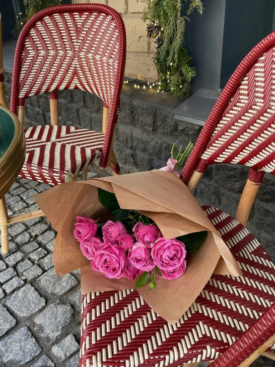 some pink roses are sitting on a table with chairs