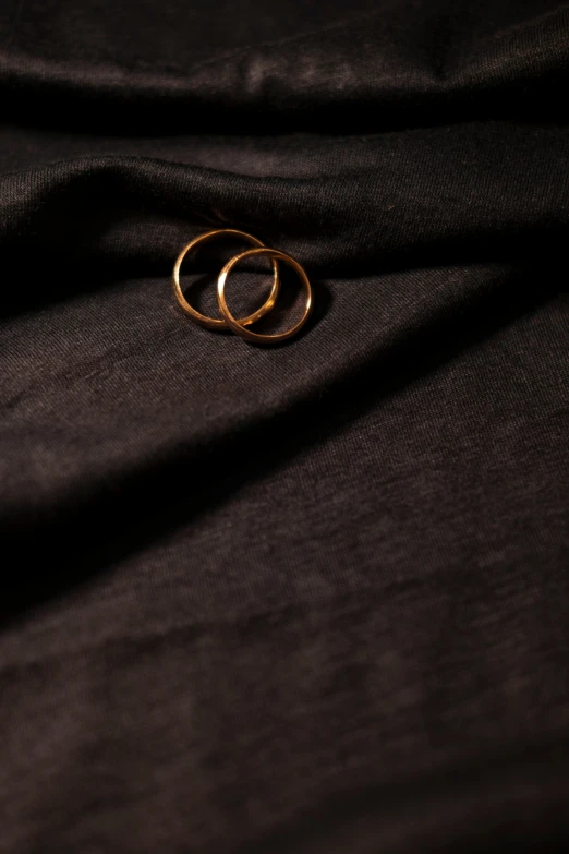 two gold rings resting on a brown fabric