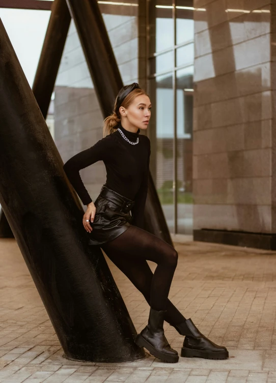 a young woman wearing black clothes standing next to a large metal structure