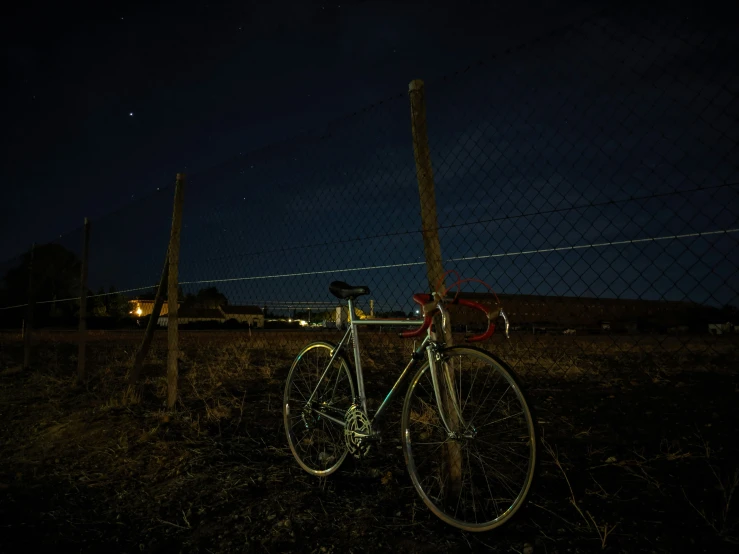 a bike sits in a grassy area, illuminated by light from headlights