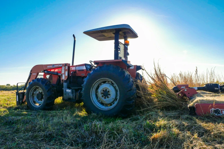 an tractor sitting in a field with hay in the background