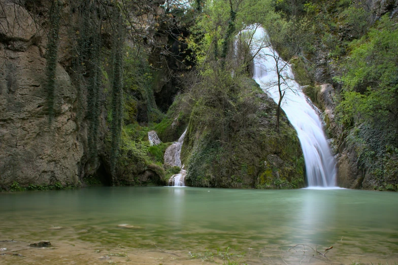 a waterfall in the jungle near rocks with trees