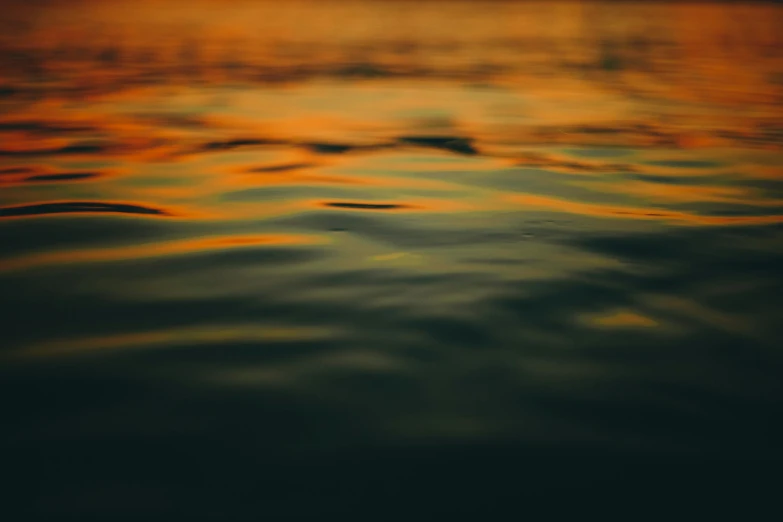 some water with small waves and an orange colored sky