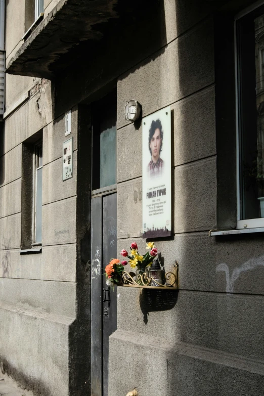 a door on the side of a gray building with flowers in front