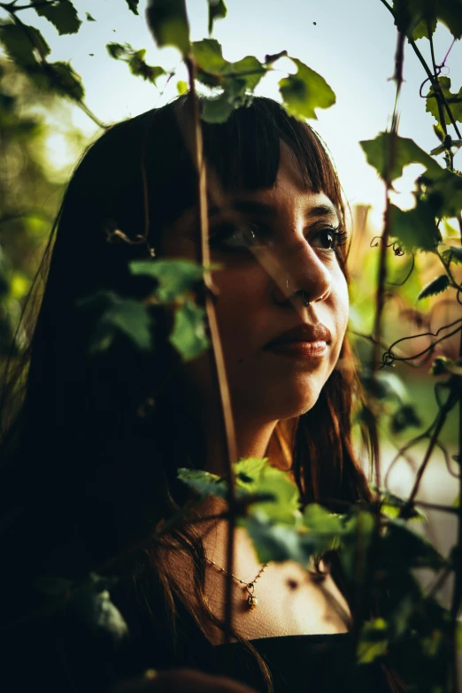 the woman stands outside in the dark by some bushes