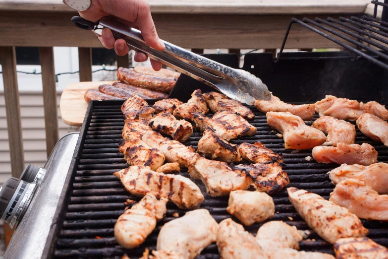 a person  up chicken and shrimp on a grill