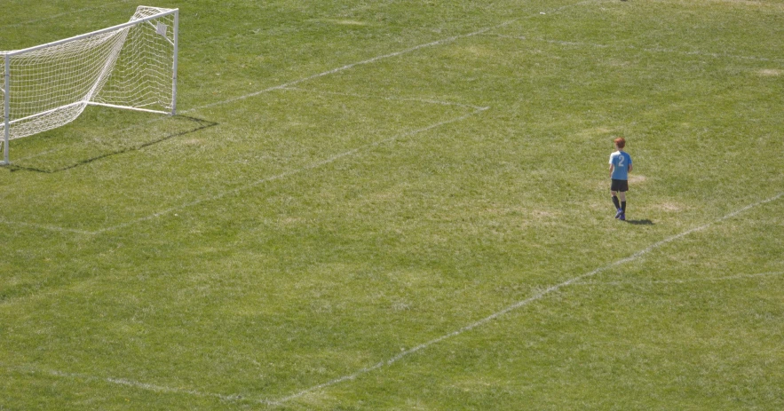 a little boy in the middle of a soccer field with a ball