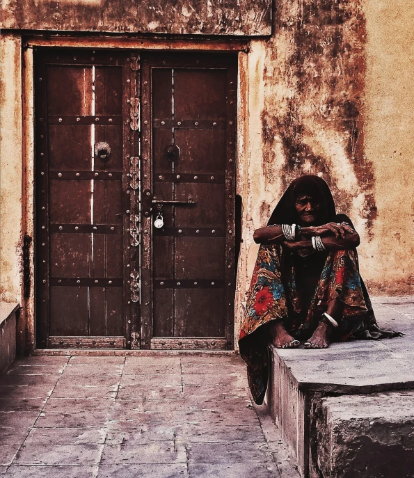 a woman sitting in front of two big doors