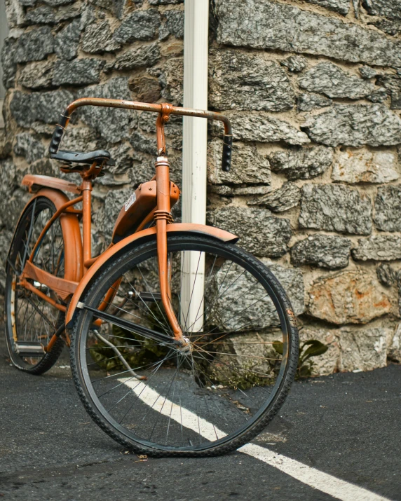 an orange bicycle is parked next to a pole