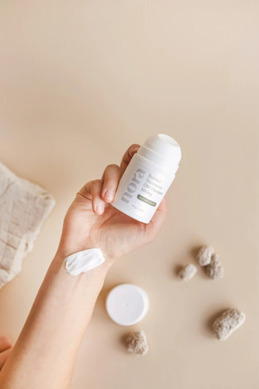 a woman holding out a small jar of skin whitening lotion