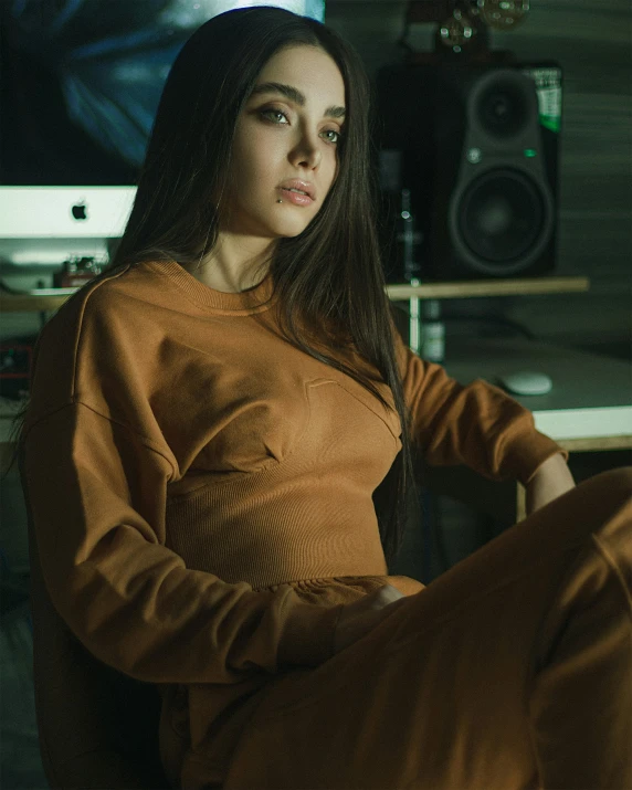 a young woman in a tan sweater sits in an office